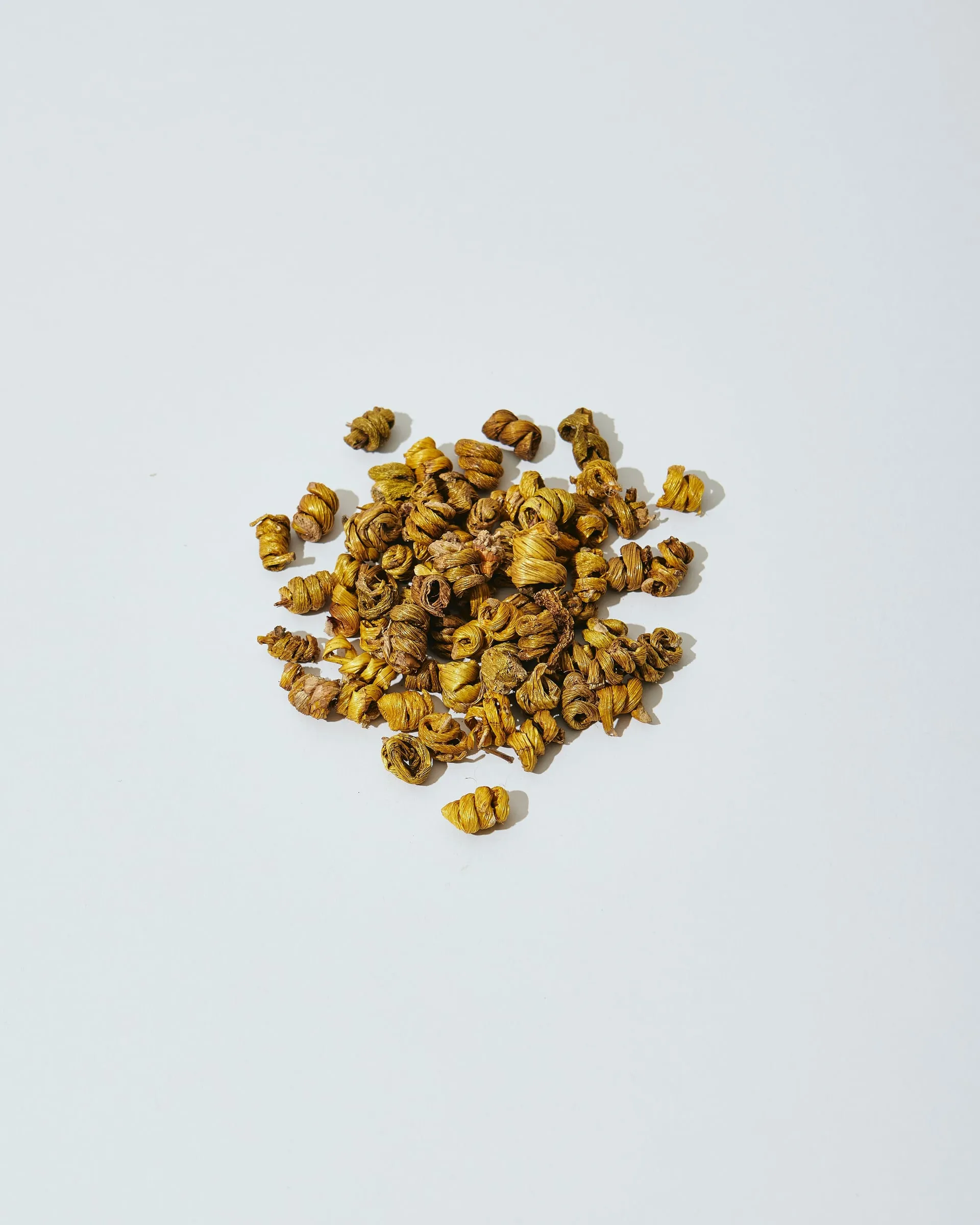 Small pile of dried, curled dendrobium on a white background